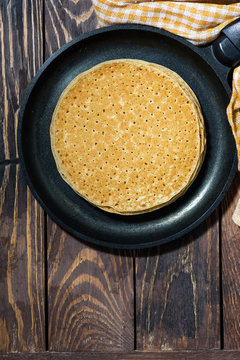 traditional thin pancakes in a frying pan, top view vertical