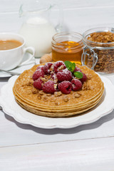 traditional thin pancakes with fresh raspberries for breakfast on wooden table, vertical