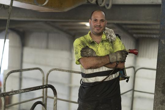 Construction worker man with non-stick liquid tank for industrial concrete mixers poses looking at camera. Real people in their work environment.
