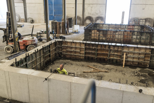 Man adjusting concrete structure in construction factory, fresh concrete