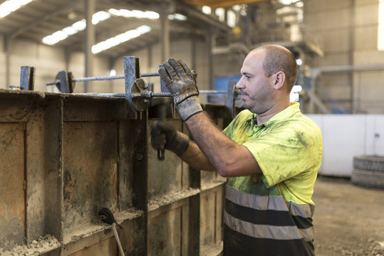 Man adjusting concrete structure in construction factory. Adjusting the mold to create a piece of cement