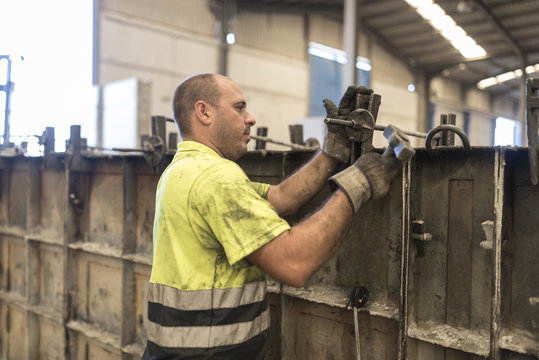 Man adjusting concrete structure in construction factory. Adjusting the mold to create a piece of cement