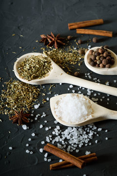  Wooden spoon with Italian seasoning-dried oregano with thyme vegetables.Oregano in a wooden spoon on a rocky concrete dark black background with a place for text.Top view.salt crystals pepper