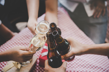 Group of  Friends toasting drinks. Close-ups hands of friends toasting wine glass  and beers in the dinner party for celebrating new year on the bokeh of light decorate on christmas tree background.