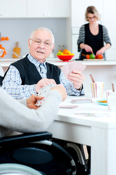 Elderly couple in wheelchairs playing cards