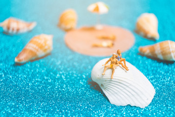 Obraz na płótnie Canvas Miniature people wearing swimsuit relaxing on a seashell