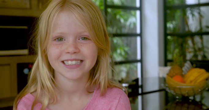 Blond haired little girl with freckles smiling and looking at camera