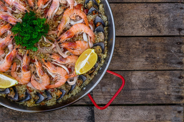 Traditional seafood paella in the fry pan on a wooden old table, top view