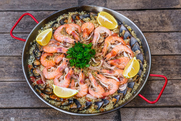 Traditional seafood paella in the fry pan on a wooden old table, top view