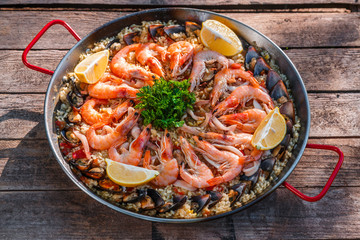 Traditional seafood paella in the fry pan on a wooden old table, top view