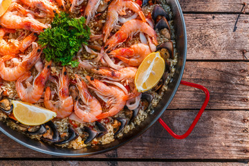 Traditional seafood paella in the fry pan on a wooden old table, top view
