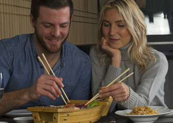 Pareja comiendo una barca de sushi en el restaurante.