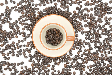 top view closeup of a coffee cup filled with roasted coffee beans o of roasted coffee beans isolated on white background .