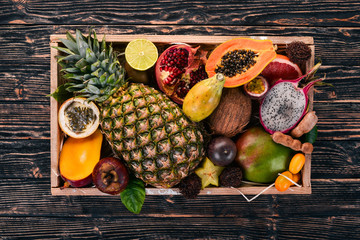 Tropical fruit in a wooden box. Papaya, Dragon Fruit, rambutan, tamarind, cactus fruit, avocado, granadilla, carambola, kumquat, mango, mangosteen, passionfruit, coconut.