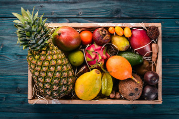 Tropical fruit in a wooden box. Papaya, Dragon Fruit, rambutan, tamarind, cactus fruit, avocado,...