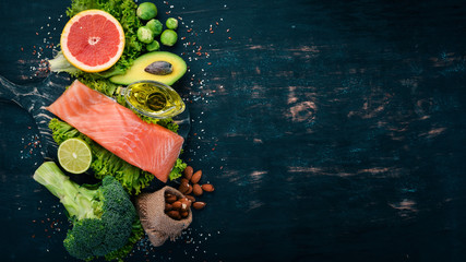 Healthy food. Fish salmon, avocado, broccoli, fresh vegetables, nuts and fruits. On a black...
