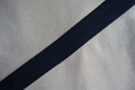 Diagonal Black Ribbon Sewn To Light Grey Fabric