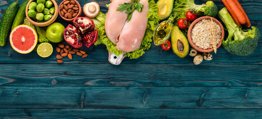 Healthy food. Chicken fillet, avocado, broccoli, fresh vegetables, nuts and fruits. On a wooden...