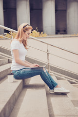 Vertical profile side view photo of beautiful cute cheerful excited blonde woman wearing ripped jeans, tshirt, is chatting with pen-friend, drinking take away coffee