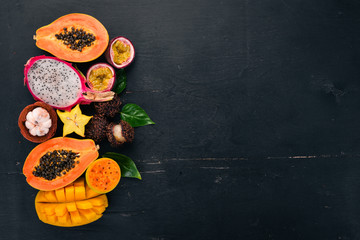 Tropical fruits, papaya, Dragon Fruit, rambutan, tamarind, cactus fruit, avocado, granadilla, carambola, kumquat, mango, mangosteen, passionfruit, coconut. On a wooden background.