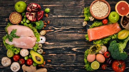 Healthy food background. Concept of Healthy Food, Chicken Fillet, Raw Meat, Fish, Avocado, Broccoli, Fresh Vegetables, Nuts and Fruits. On a wooden background. Top view. Copy space.
