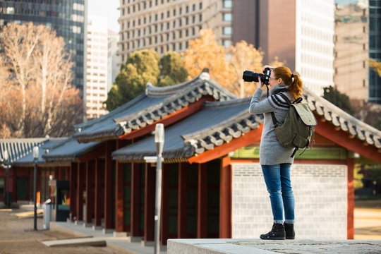 A woman traveler photographs an ancient palace in South Korea