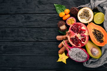 Dragon fruit, papaya, kumquat, hranadylla, avocado, passion fruit. Tropical Fruits. On a wooden background. Top view. Copy space.