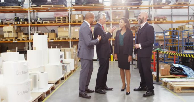 4K Cheerful business team in suits chatting in large warehouse. Slow motion.