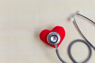 Stethoscope with Strong red heart on wood table on doctor desk with copy space. Check up health for buy insurance concept.
