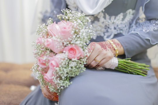 Bride hand with henna and a bouquet of flower.