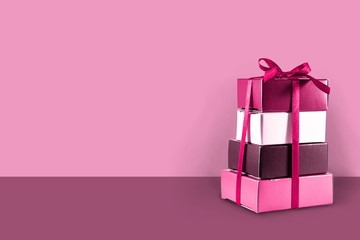 Gift boxes stacked on a pink background with copy space, concept for Valentine's Day, Mother's Day, Christmas, birthday and anniversary.