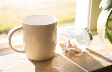 Coffee mug with brown sugar tubes on wooden table