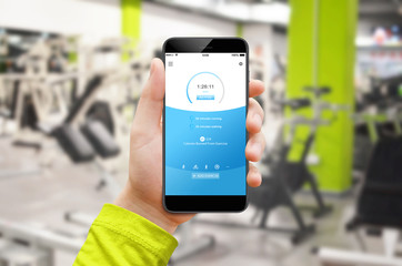 Male hand holding phone with fitness app while training in gym. Fitness gadget.
