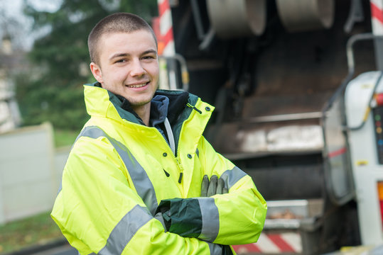 young garbage collector standing near his truck