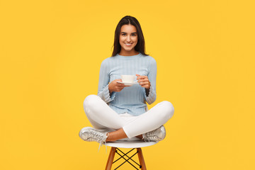 Charming girl with coffee cup on chair