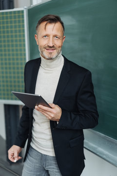 Confident teacher holding a tablet in classroom