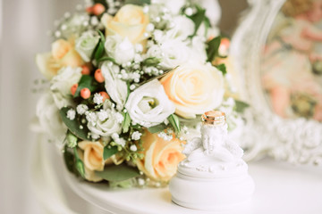 gold wedding rings on bride's bouquet of white and delicate beige roses, wedding decor