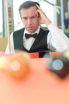 thoughtful man with suit sitting posing in billiard pool