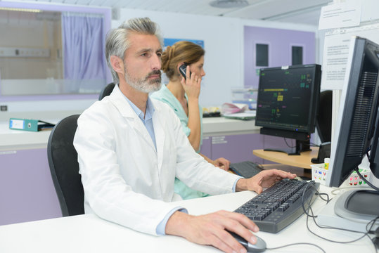 mature handsome doctor looking at exam results on the computer