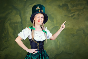 A girl dressed as St. Patrick points with her finger against a green background. St. Patrick's Day.