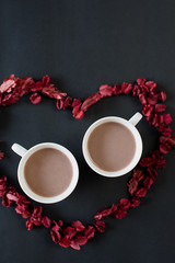 Two cups of coffee in a red heart on the black background