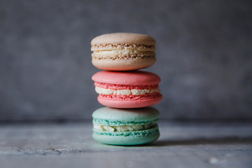 Fototapeta na wymiar Macaroon. Macaron on gray neutral loft background, stand on plate of different colors. Wooden background.