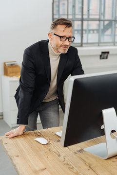 Businessman standing reading a desktop monitor