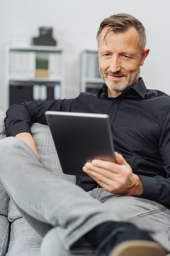 Man sitting reading a handheld tablet