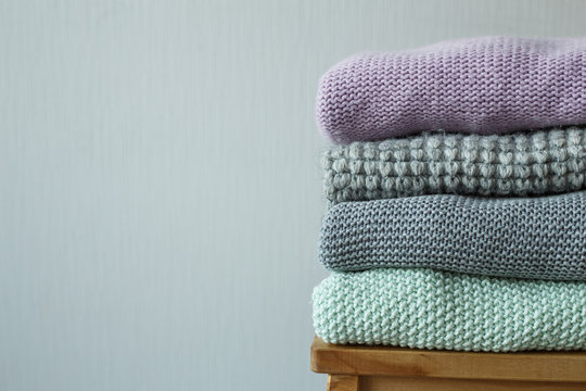 Stack of cozy knitted clothes on a wooden ladder.