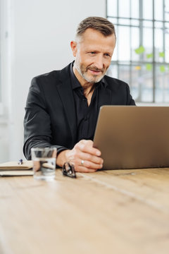 Businessman sitting peering at his laptop screen