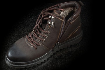 One new brown suede winter boot on a dark granite, top view