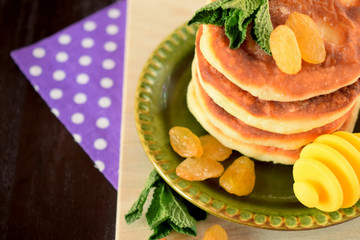 Cottage cheese pancakes, syrniki decorated with raisins and mint on a little plate 