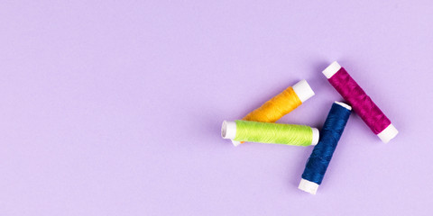 colorful yarn for sewing on purple background panorama
