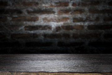 Wood table top on old dark brick wall background.